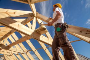 A worker is shown building the frame of a new home.