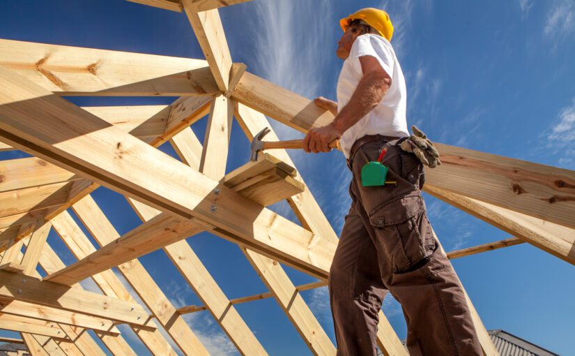 A worker is shown building the frame of a new home.